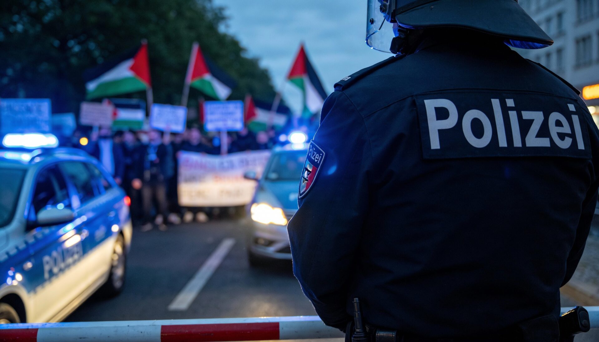 Polizist im Einsatz bei einer Demonstration, im Hintergrund unscharfe Protestschilder und Blaulicht – Symbolbild für die Strafverfolgung antisemitischer Straftaten